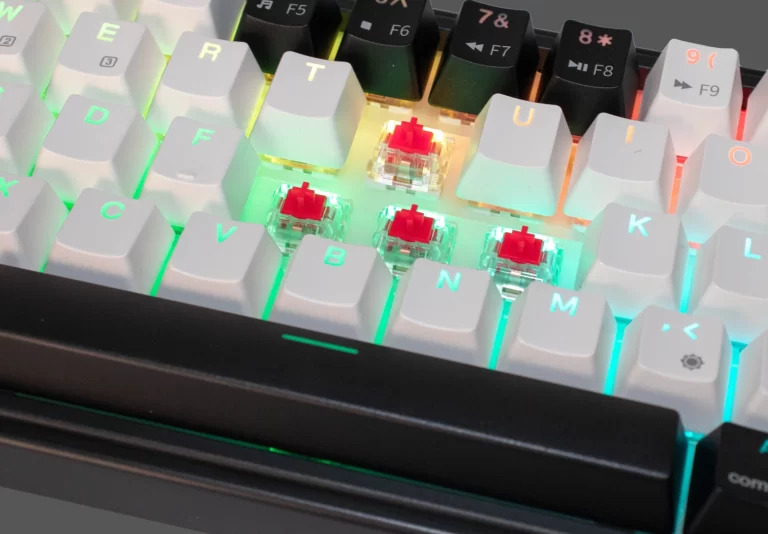 Vista superior del teclado Okami EX65 con teclas blancas iluminadas en RGB verde y switches rojos.